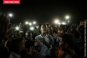 En couverture du catalogue du World Press Photo 2020, la photo 1er Prix : "Une Voix dans le Noir", un jeune homme récitant un poème pour la liberté et le retour à un régime civil, à la lumière de téléphones portables, lors d'une manifestation à Khartoum en 2019©Yasuyoshi Chiba, Japon/AgenceFrance-Presse 